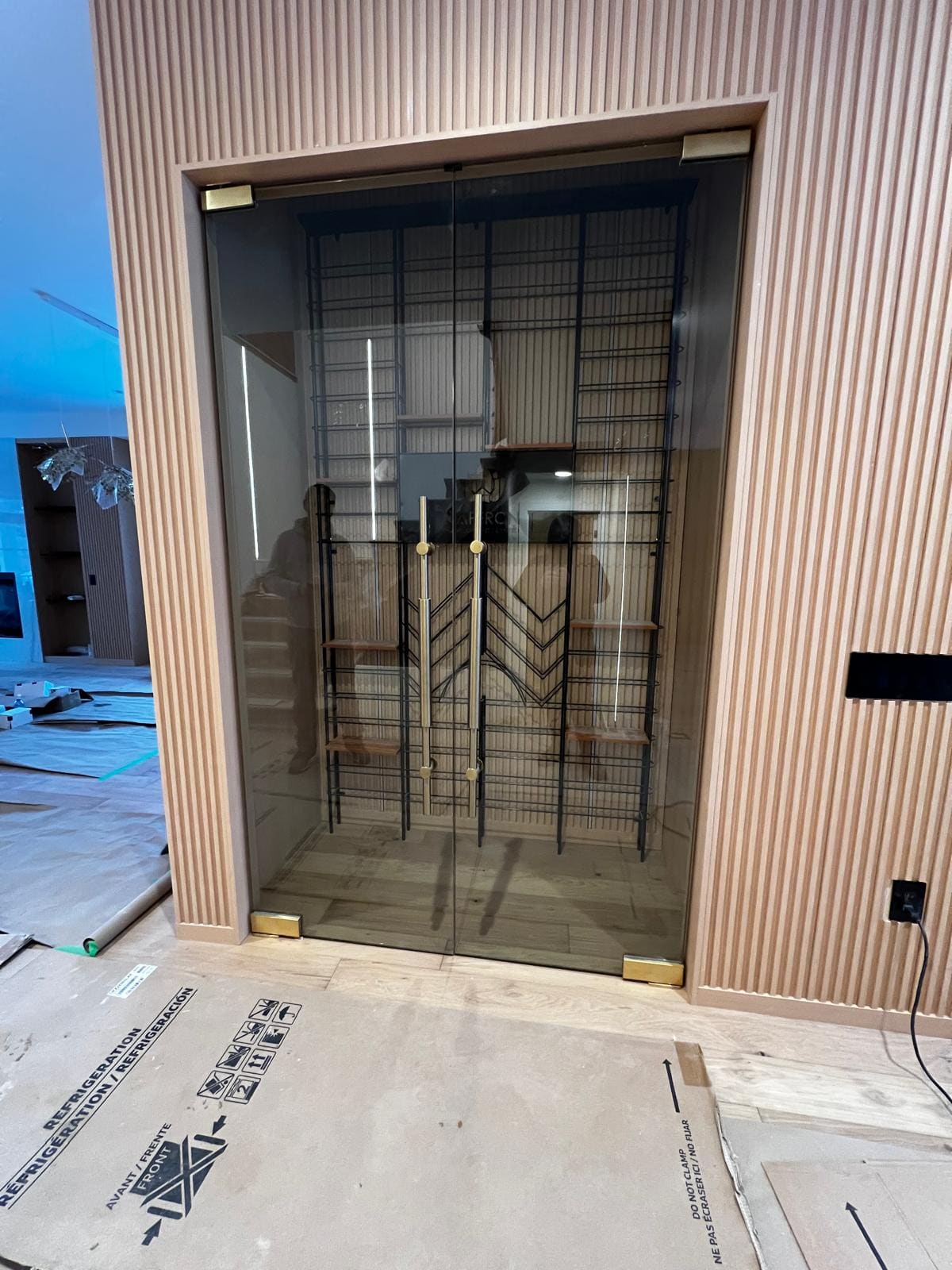Glass wine room doors with brass pulls in a fluted wall