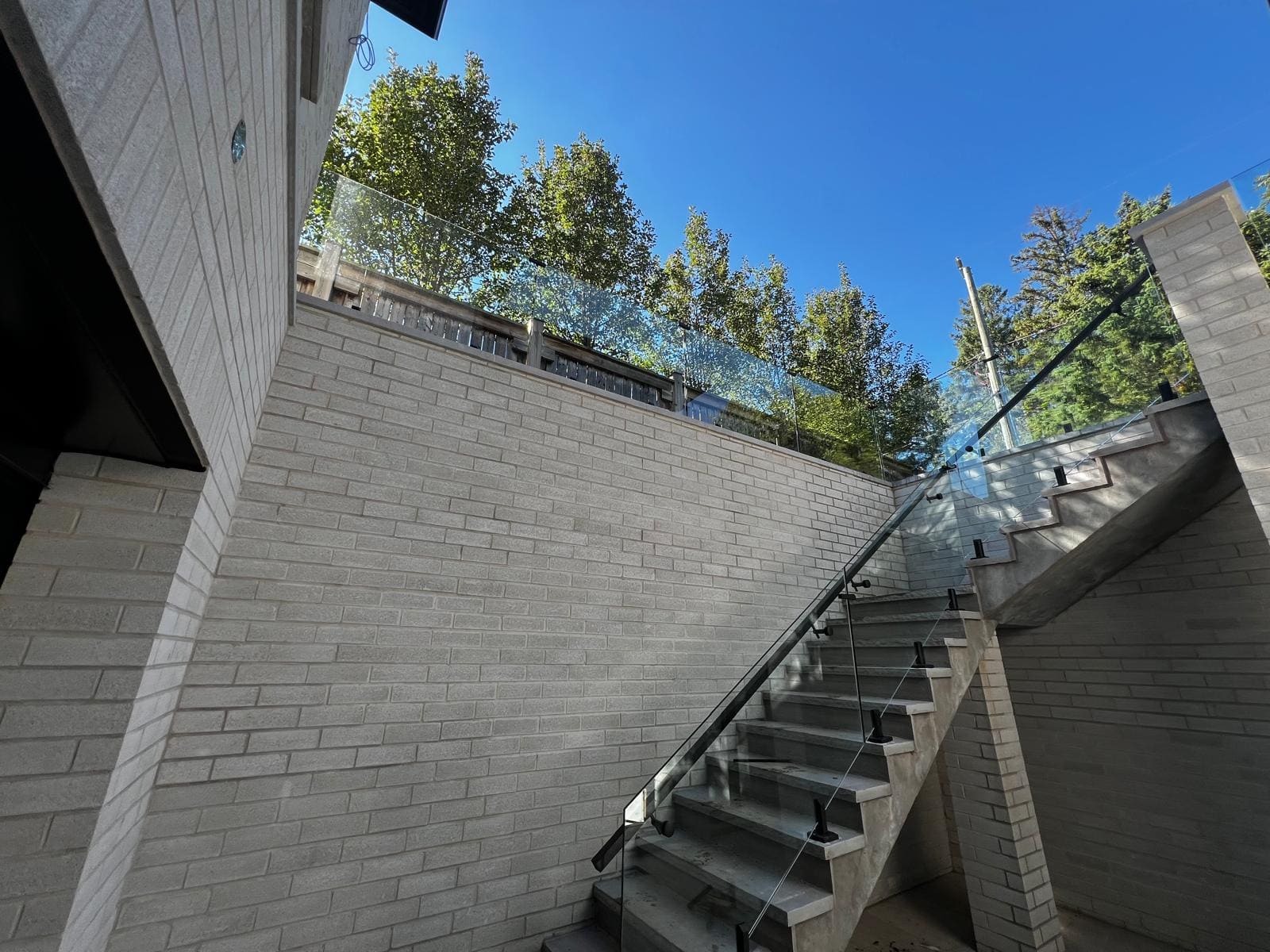Glass-guarded exterior stair along a brick retaining wall