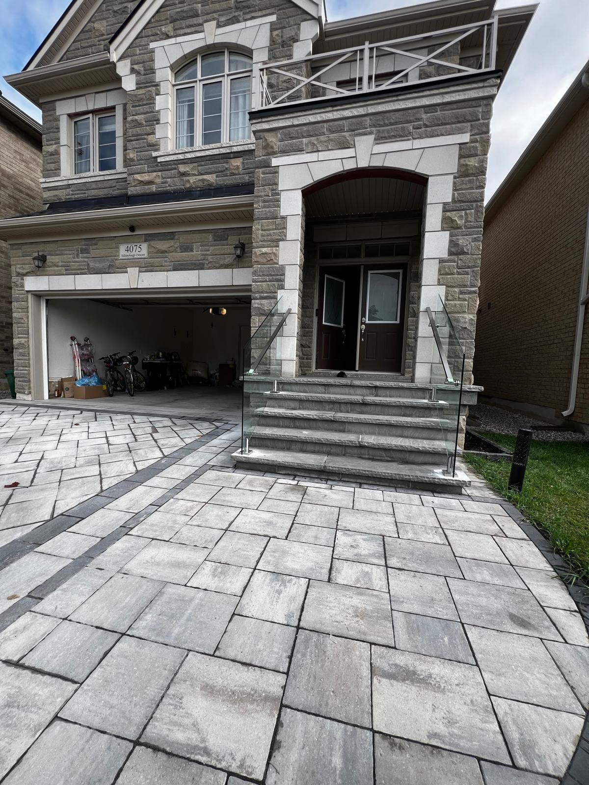 Frameless glass and a stainless handrail on a wide stone entry stair