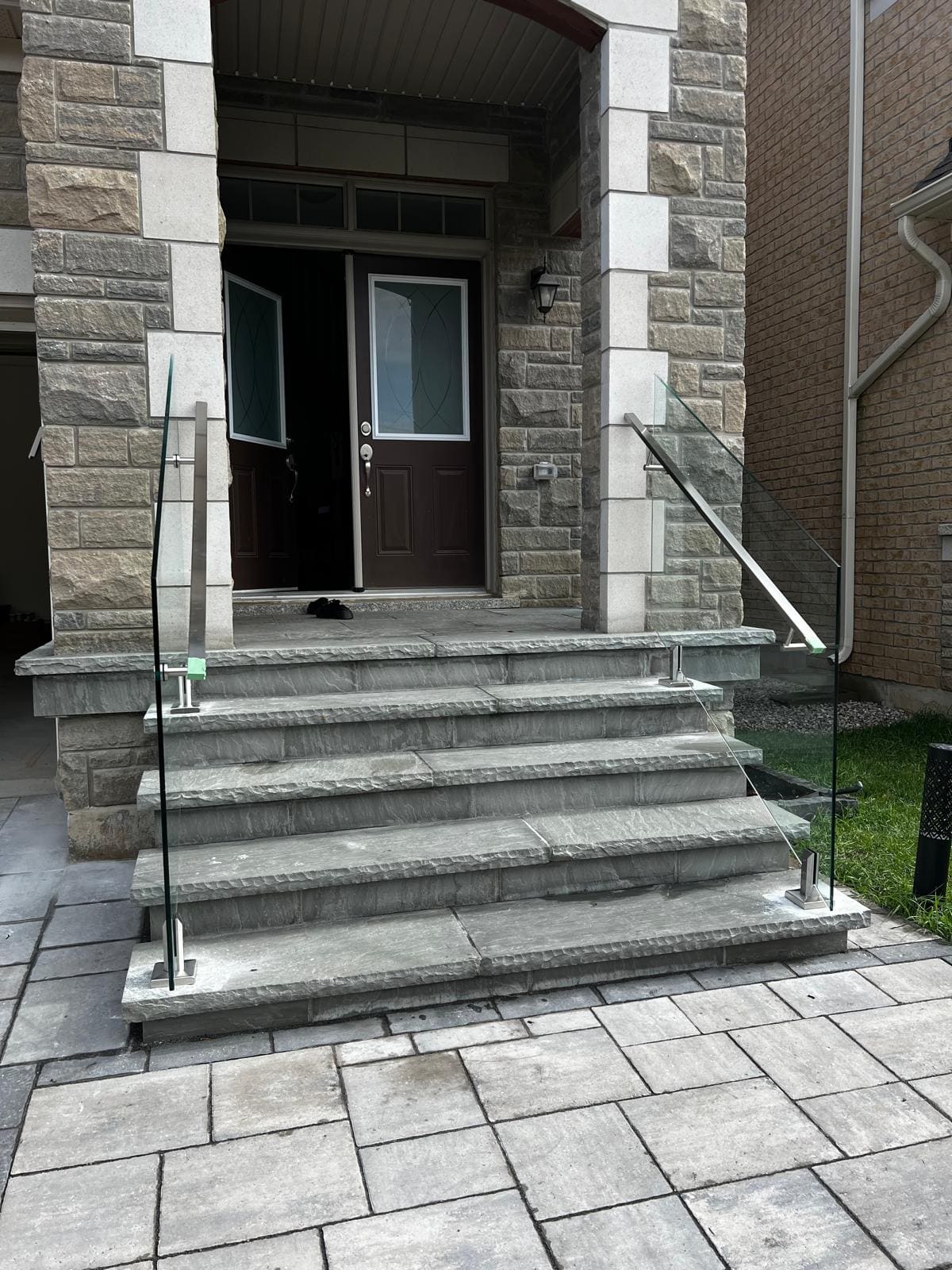 Frameless glass and a stainless handrail on a wide stone entry stair