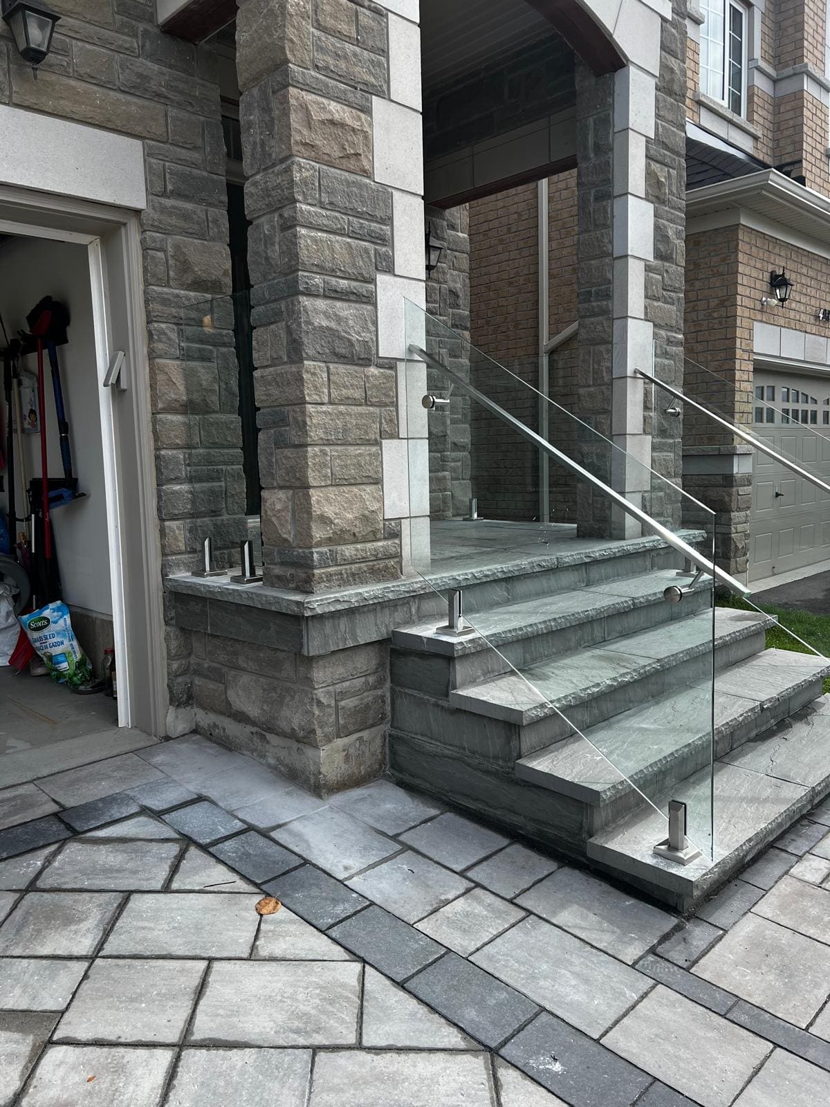 Frameless glass and a stainless handrail on a wide stone entry stair