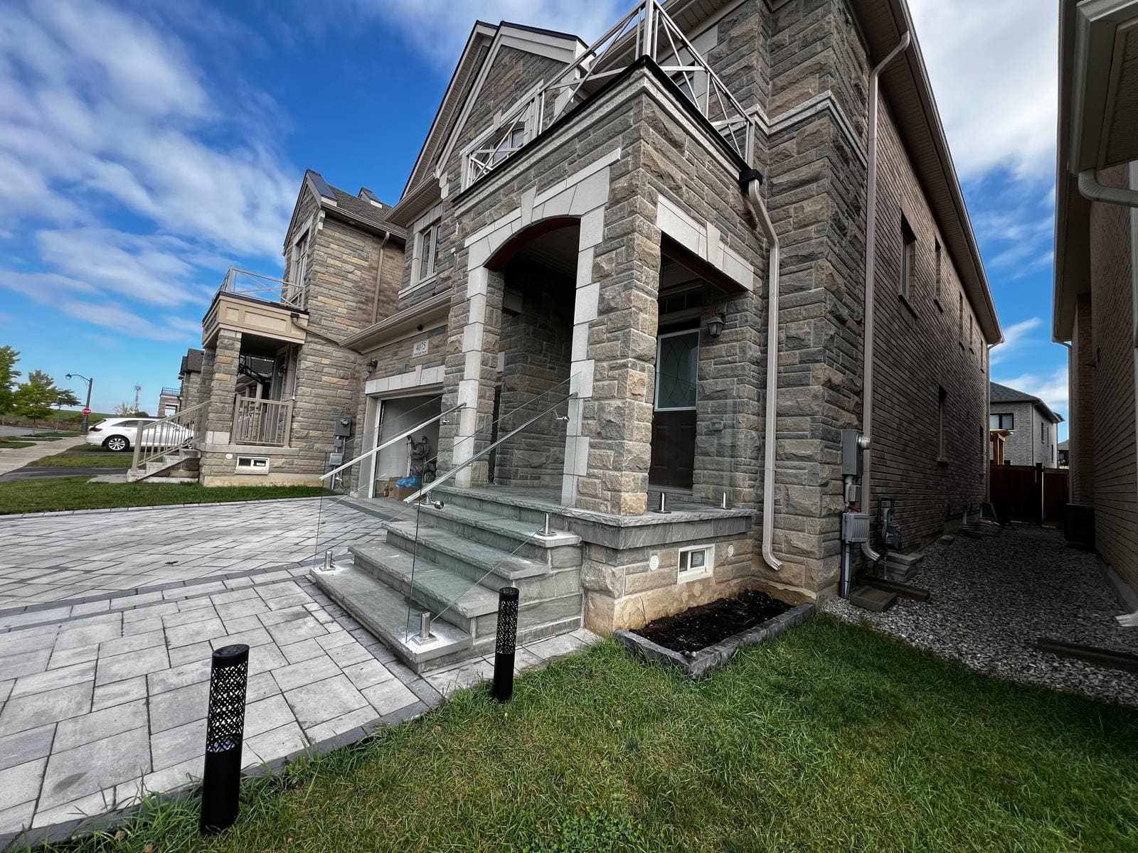 Frameless glass and a stainless handrail on a wide stone entry stair