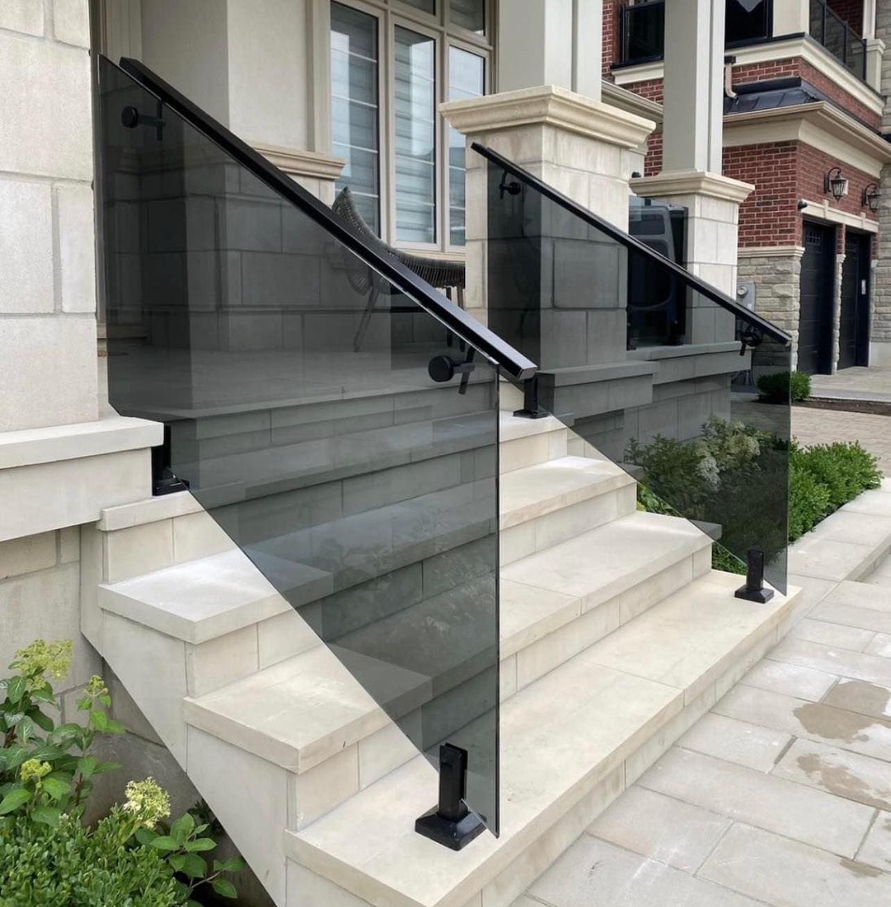 Grey-tinted glass with a black handrail on a cut-stone entry stair