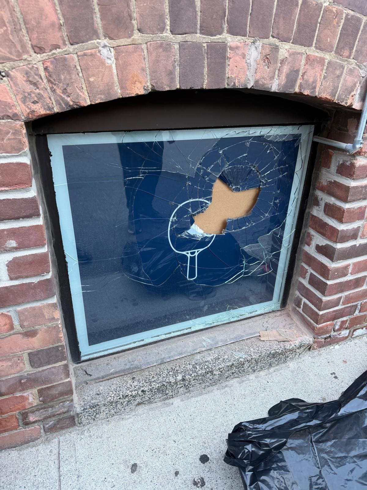Broken basement window in a brick wall, replaced
