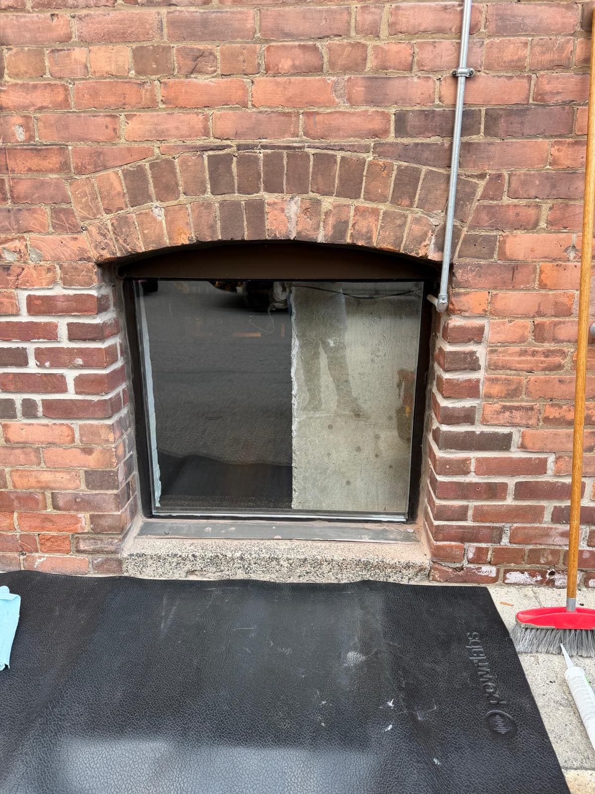 Broken basement window in a brick wall, replaced