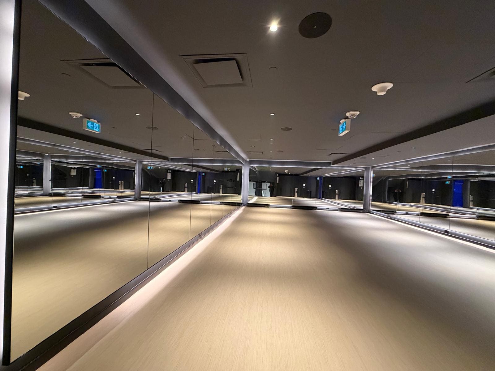 Mirror wall above a lit reveal in a commercial fitness studio