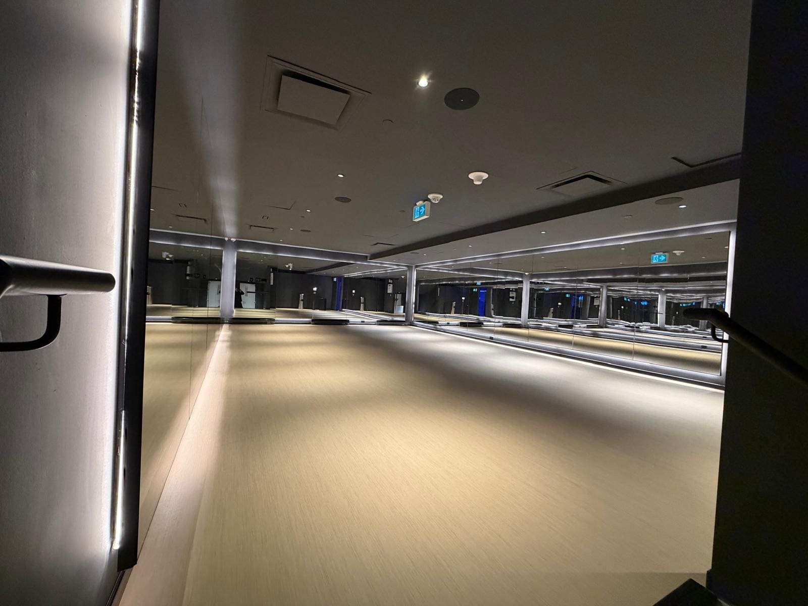 Mirror wall above a lit reveal in a commercial fitness studio