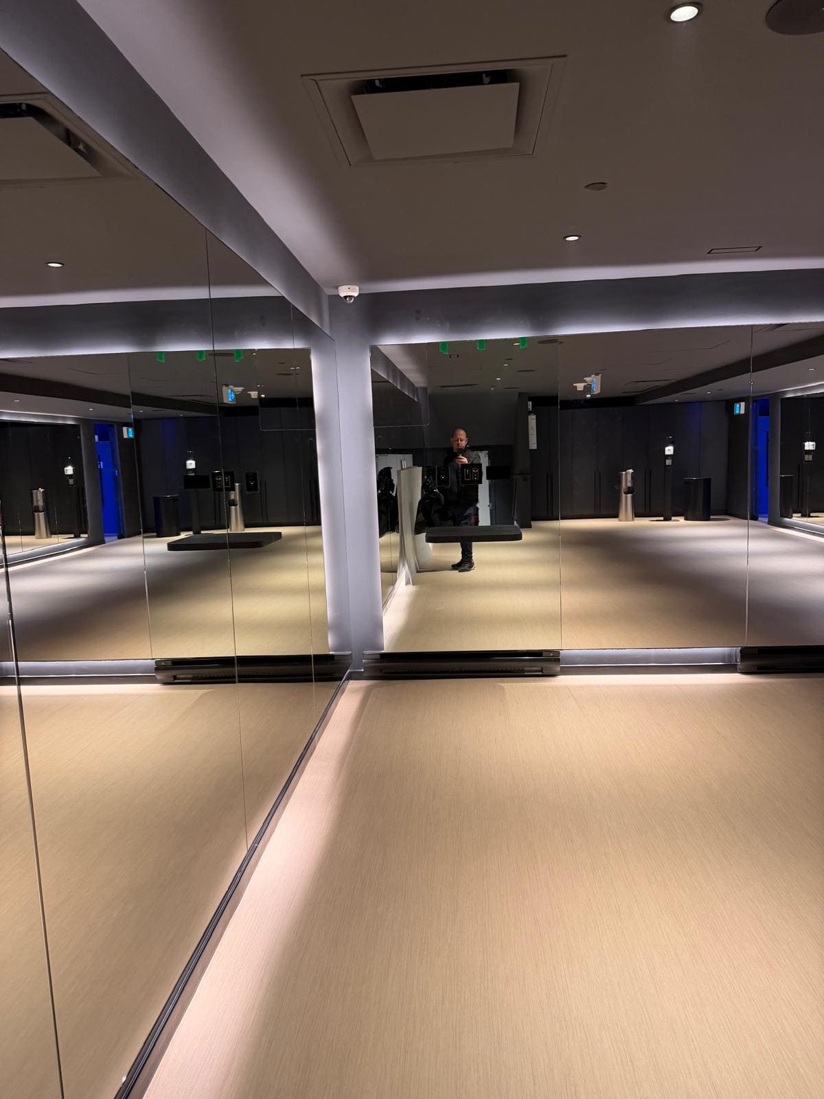 Mirror wall above a lit reveal in a commercial fitness studio