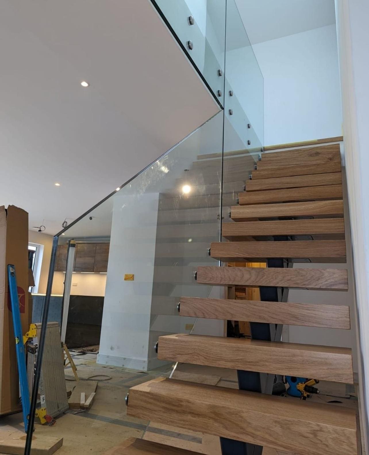 Full-height glass on standoffs beside a floating oak stair