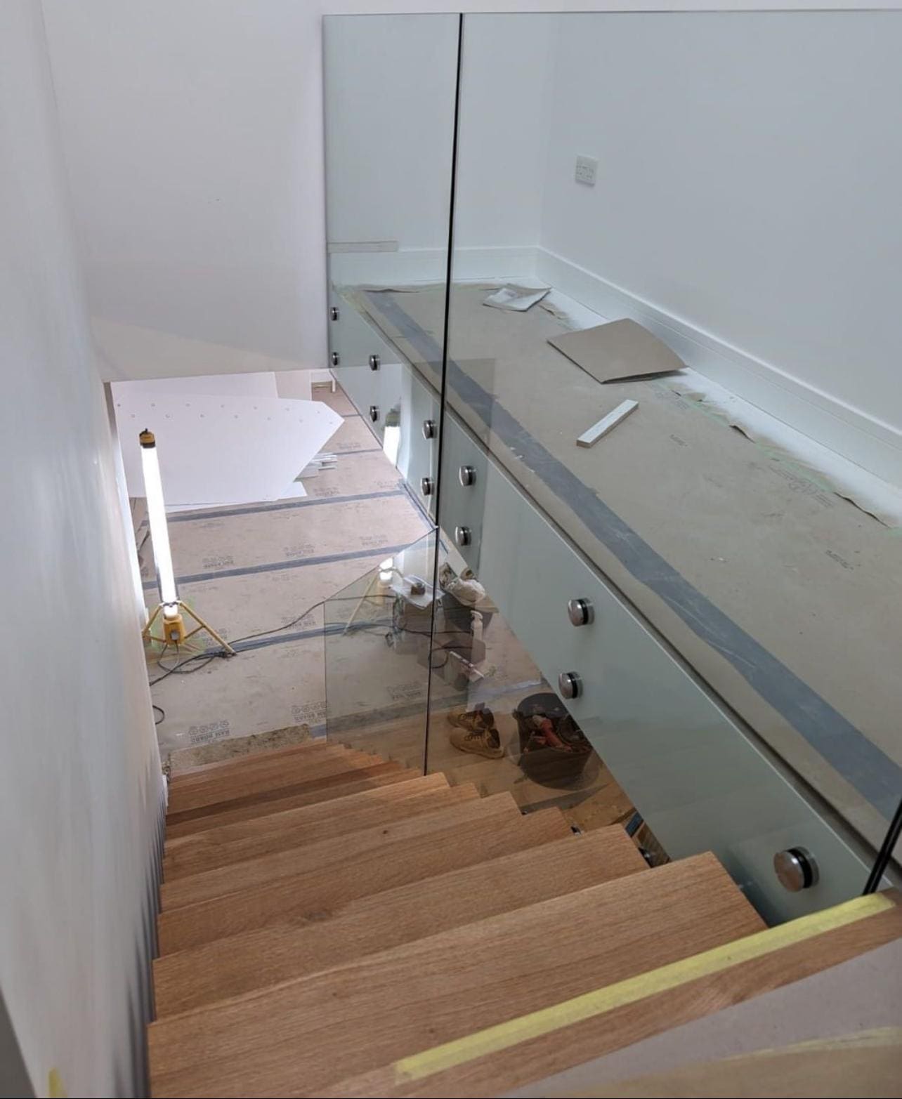 Full-height glass on standoffs beside a floating oak stair