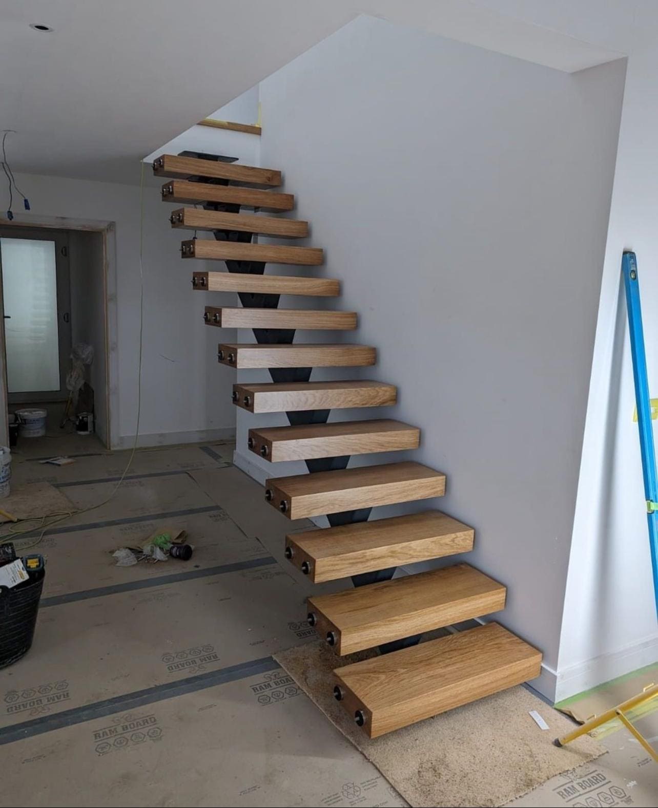 Full-height glass on standoffs beside a floating oak stair