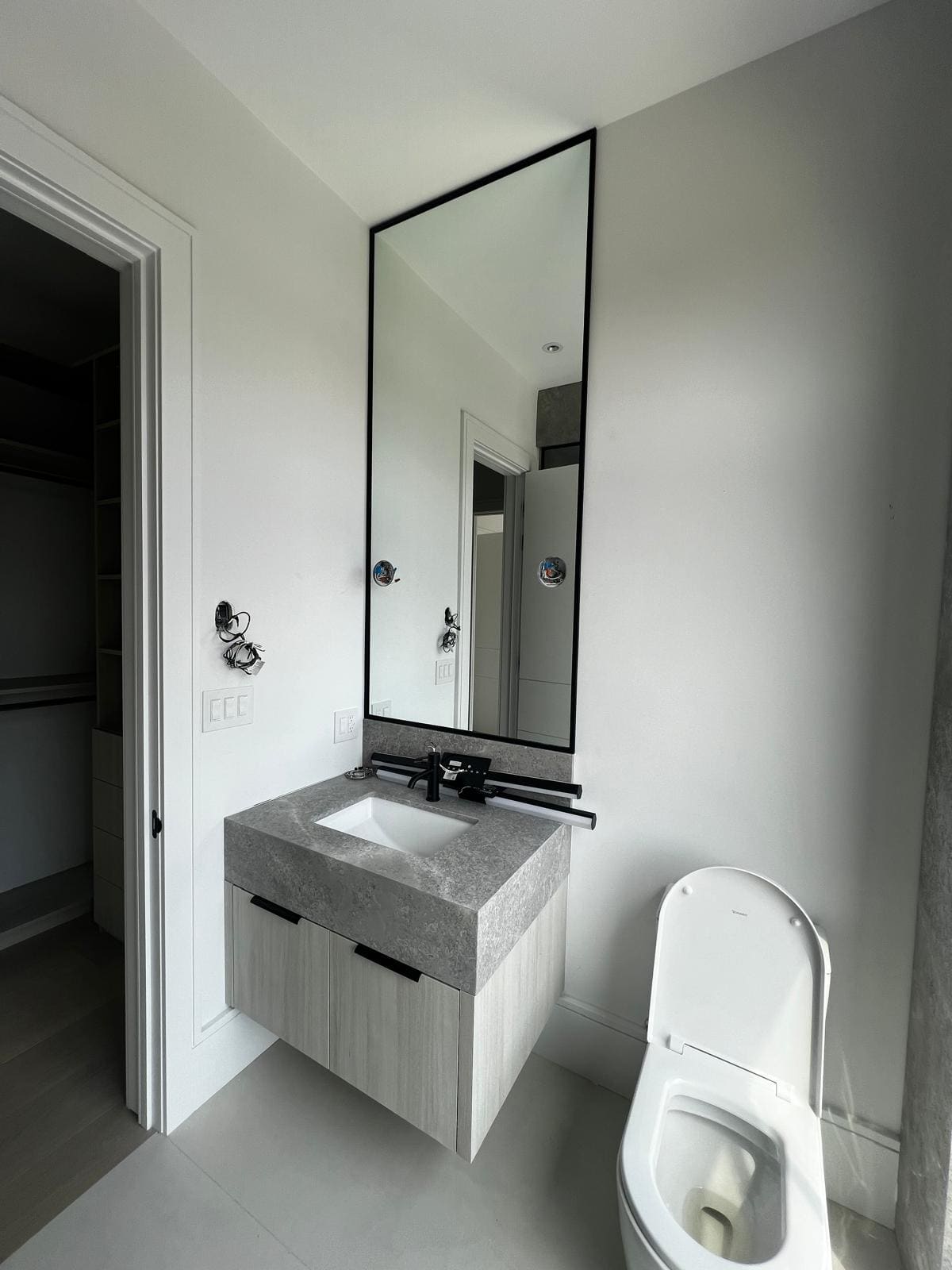 Tall black-framed mirror over a marble vanity