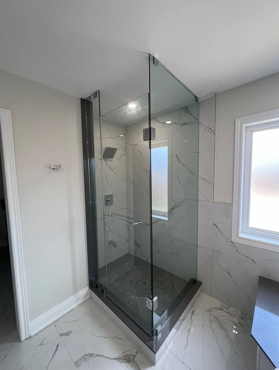 Frameless corner shower beside a window