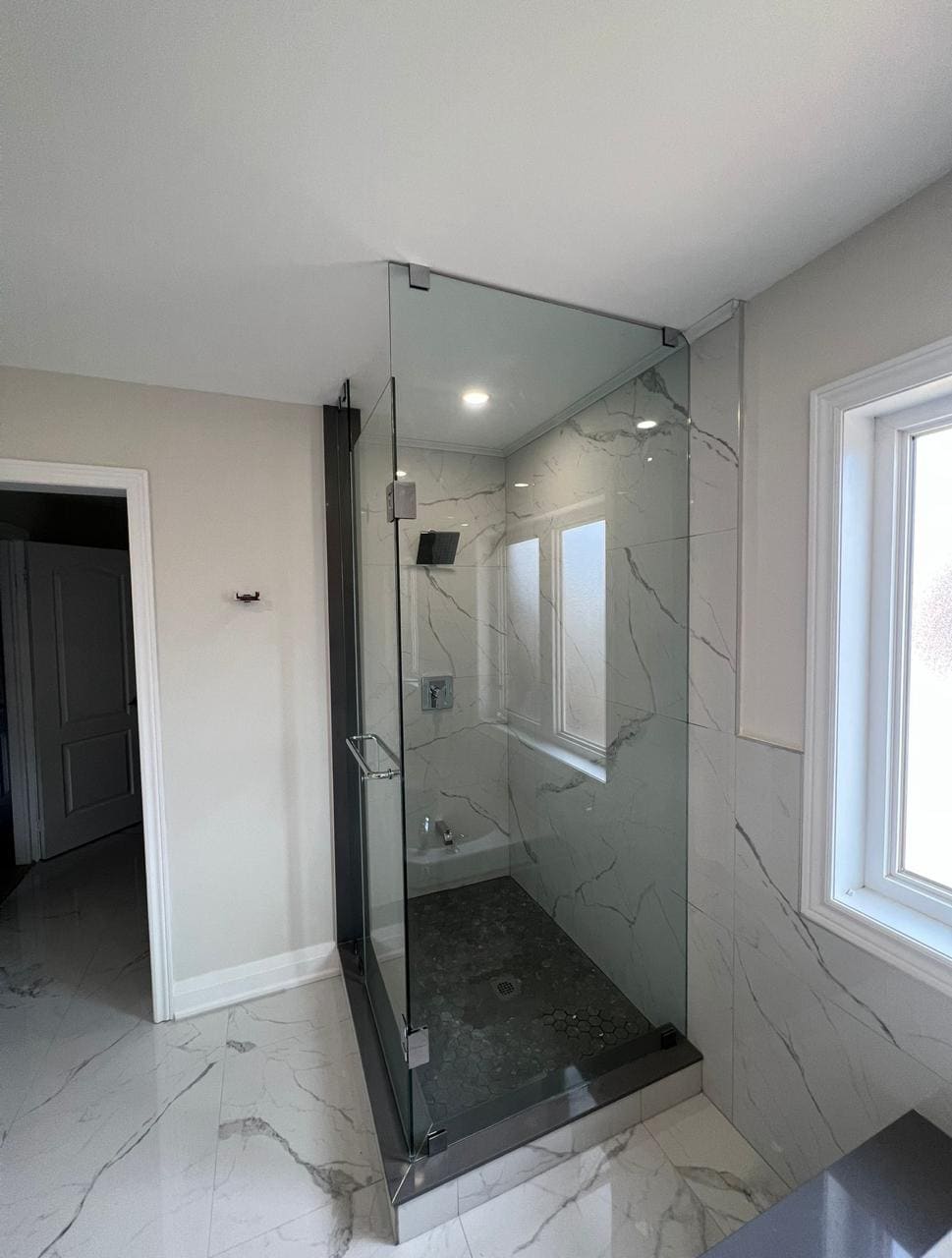 Frameless corner shower beside a window