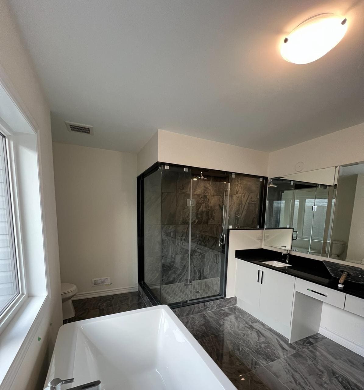 Floor-to-ceiling glass enclosure in a grey marble ensuite