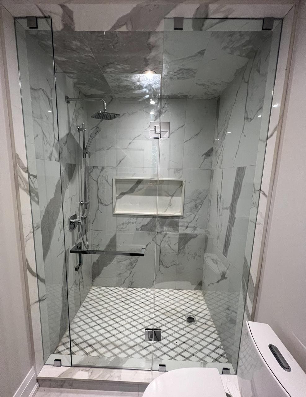 Frameless panel and door on a marble walk-in shower