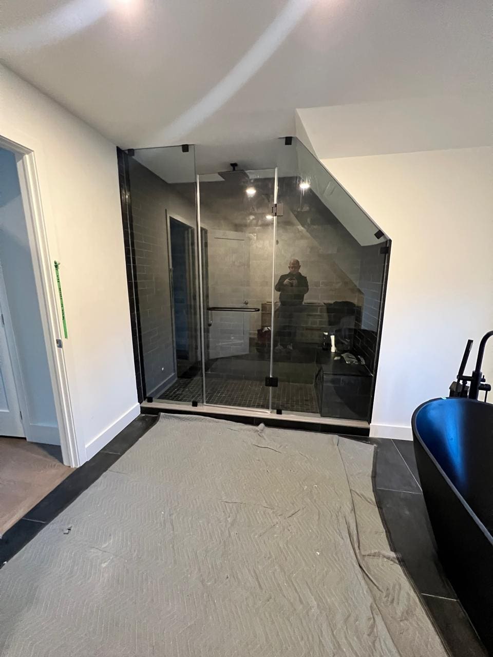 Glass cut to a sloped ceiling over a dark-tile shower
