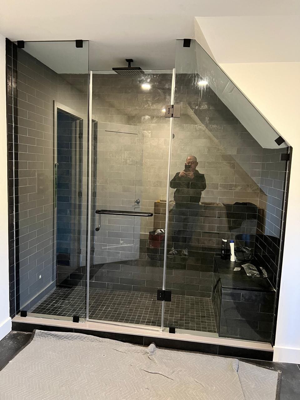 Glass cut to a sloped ceiling over a dark-tile shower