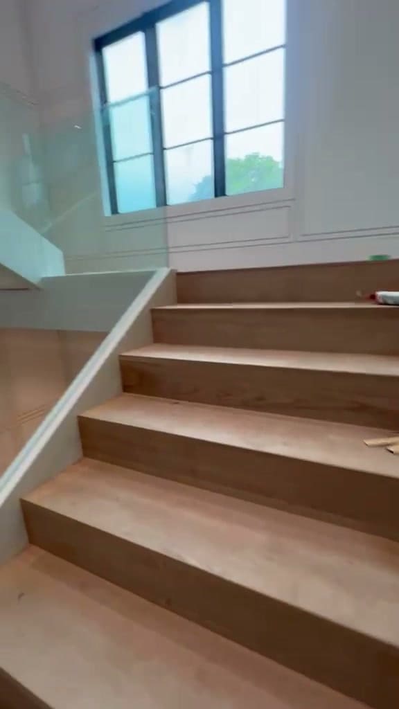 Walking down a switchback stair guarded in frameless glass